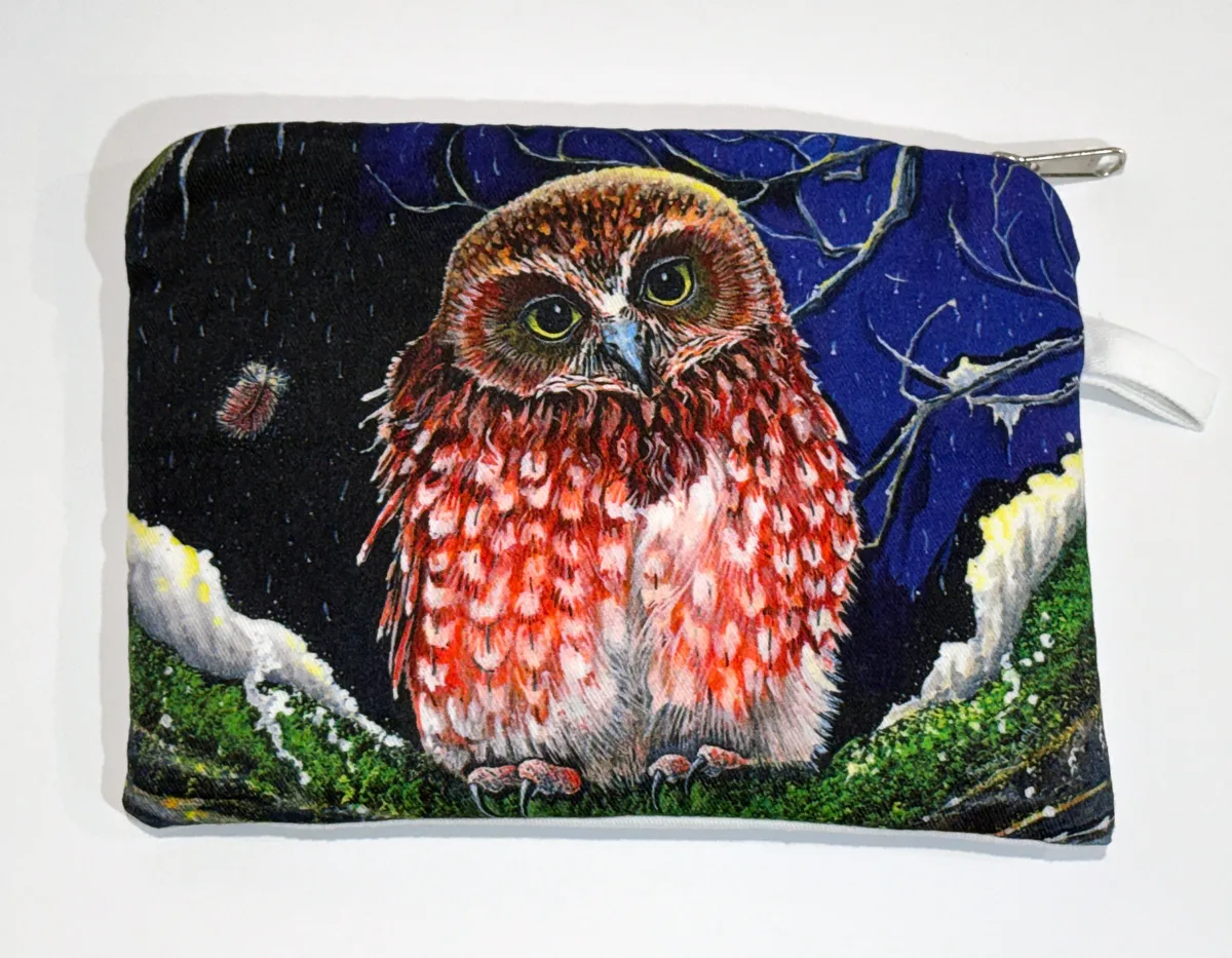 A zip-up cotton pouch printed with a small rusty-red boobook owl with large yellow-green eyes, perched on a mossy branch against a starry night sky of deep blue and black.