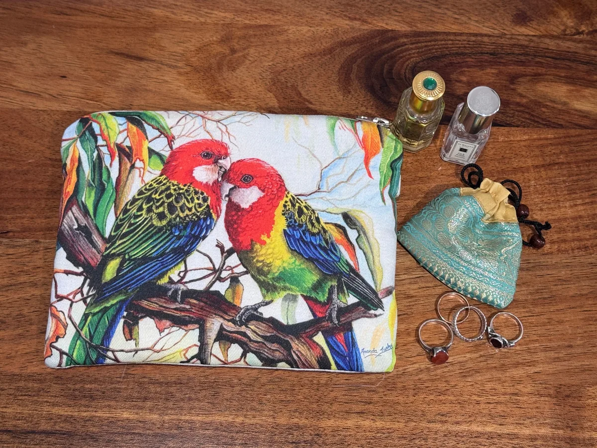 The eastern rosellas pouch beside rings, a small silk pouch and two perfume bottles, showing its size.