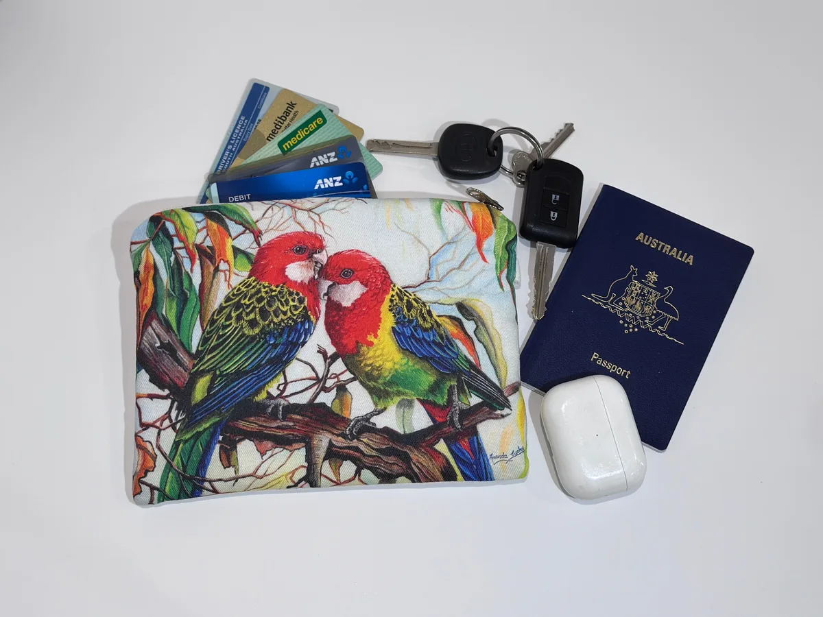 The eastern rosellas pouch beside keys, cards, a passport and earbuds, showing its size.