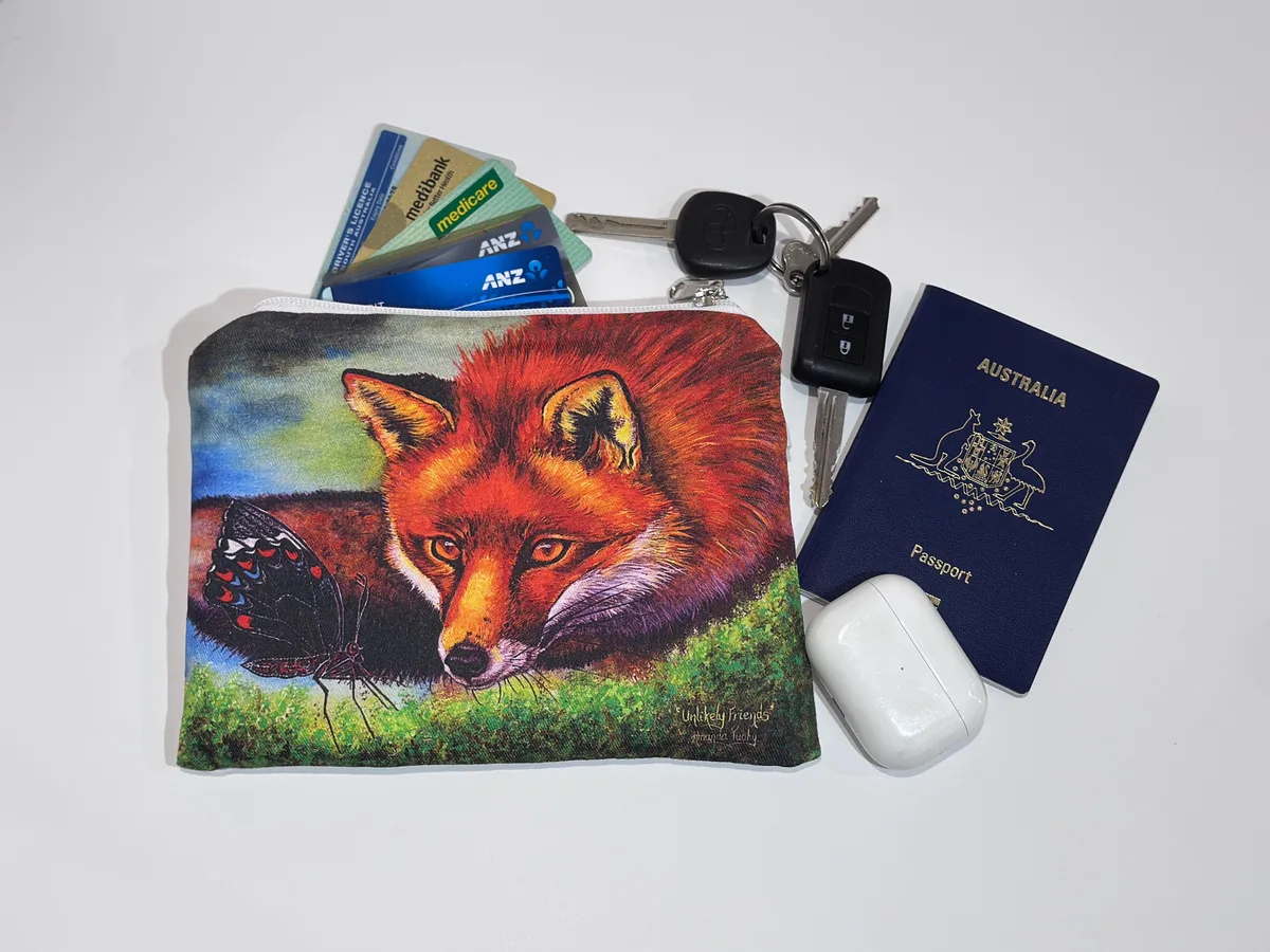 The fox pouch beside keys, cards, a passport and earbuds, showing its size.