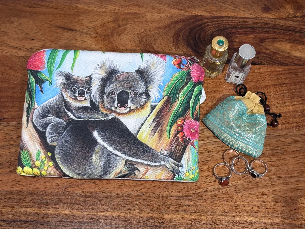 The koalas pouch beside rings, a small silk pouch and two perfume bottles, showing its size.