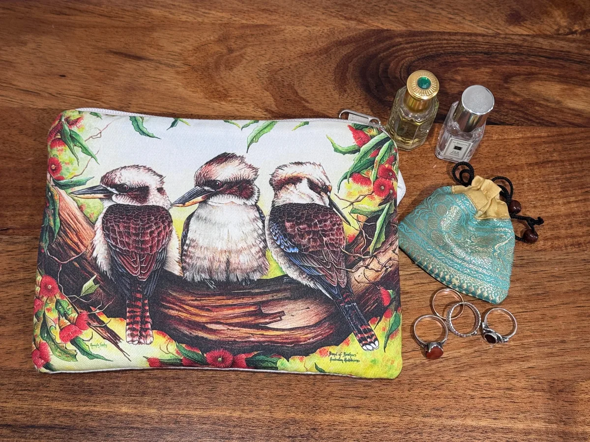 The kookaburras pouch beside rings, a small silk pouch and two perfume bottles, showing its size.