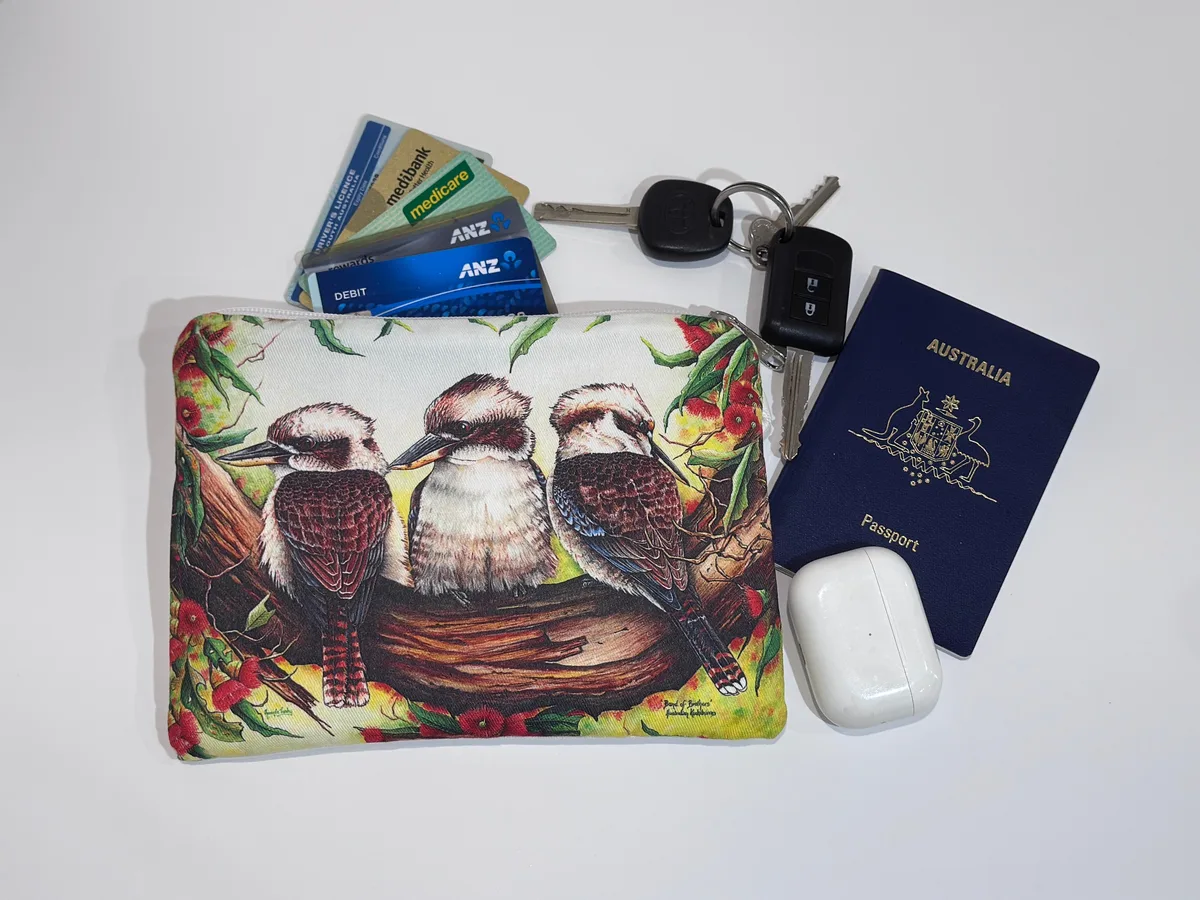 The kookaburras pouch beside keys, cards, a passport and earbuds, showing its size.