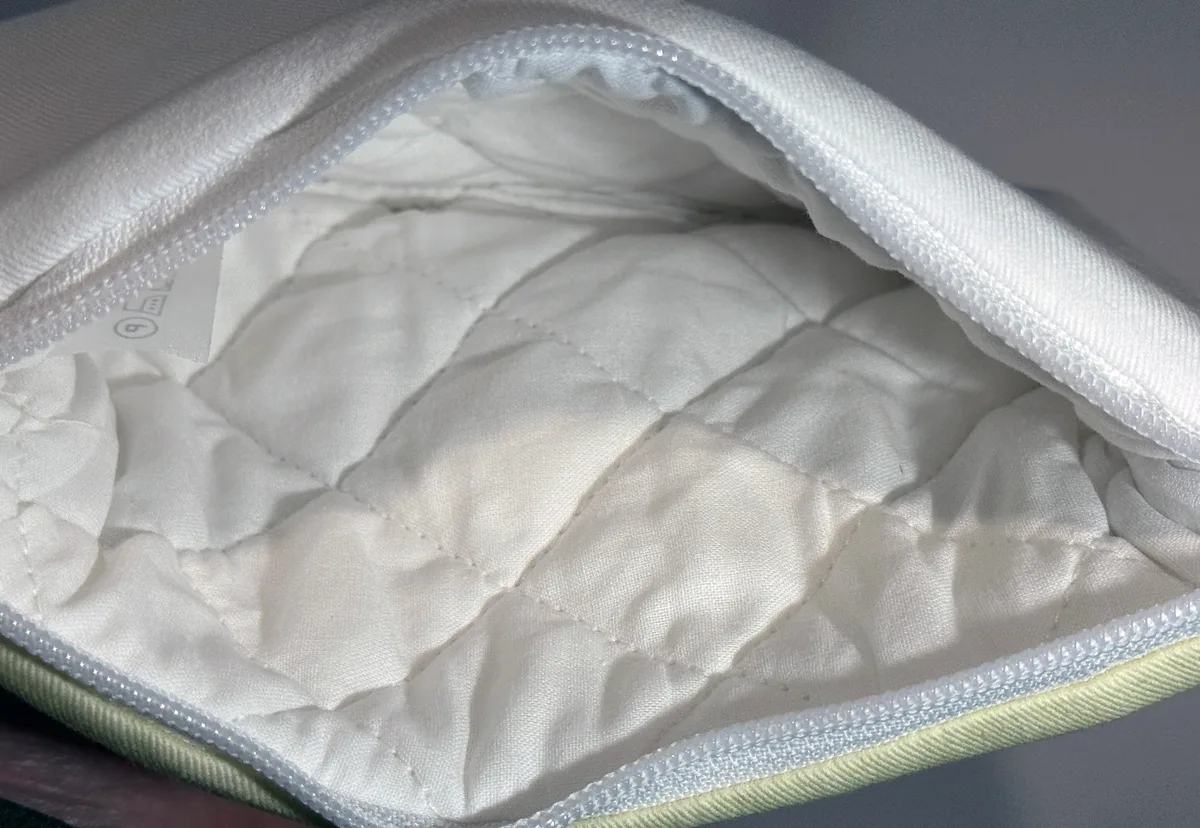 The inside of an open pouch, showing its quilted white lining and zip.