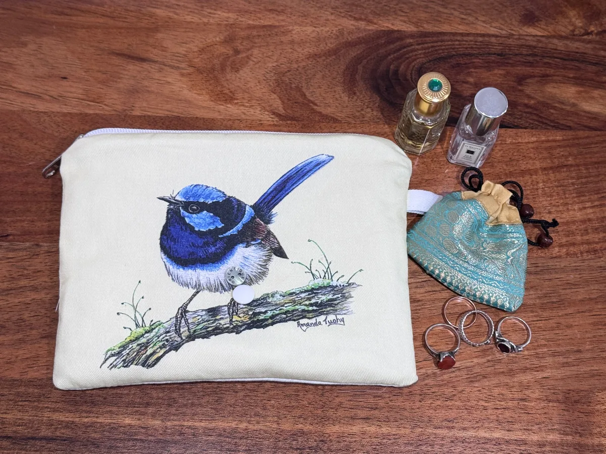 The single wren pouch beside rings, a small silk pouch and two perfume bottles, showing its size.