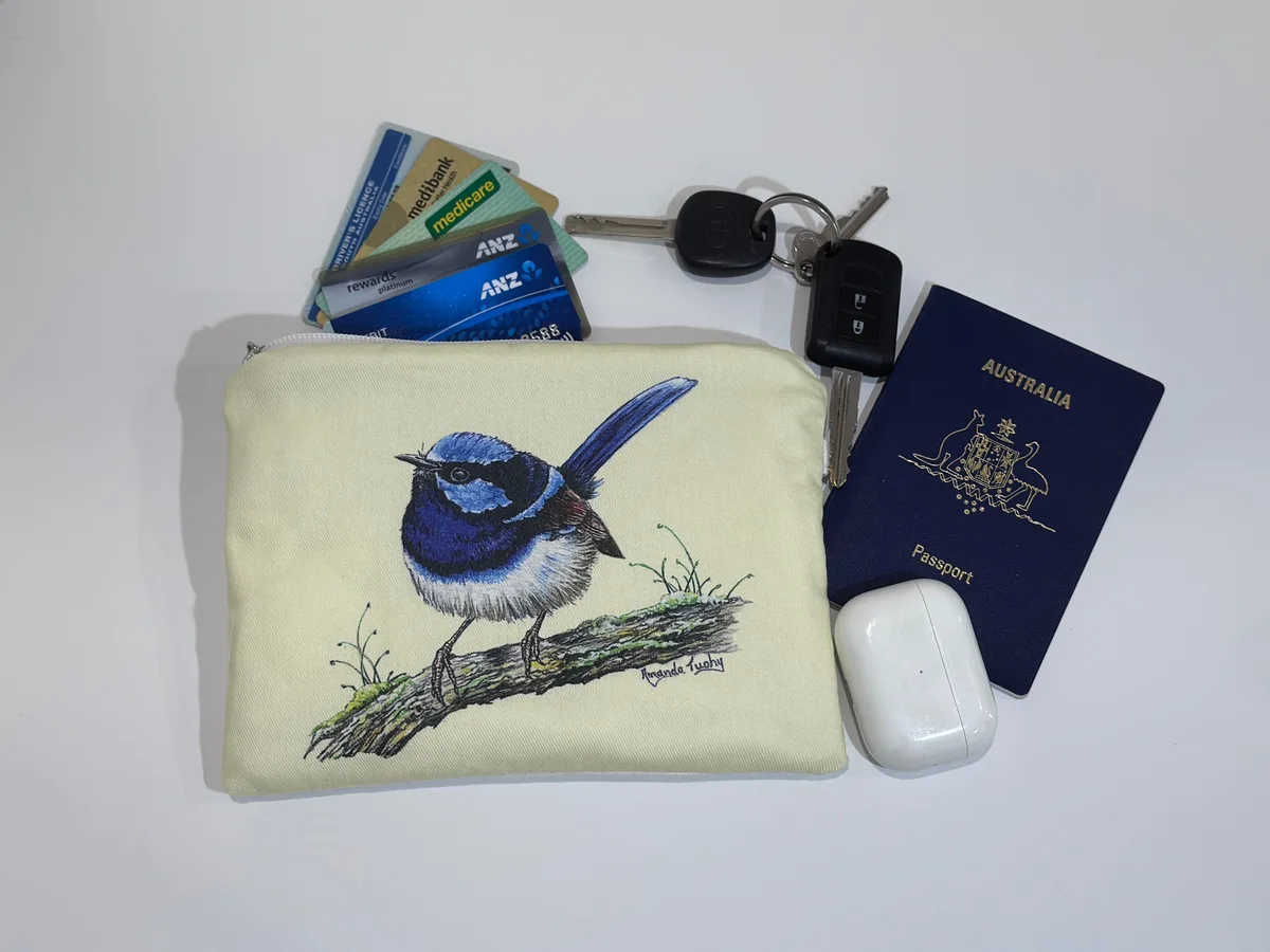 The single wren pouch beside keys, cards, a passport and earbuds, showing its size.