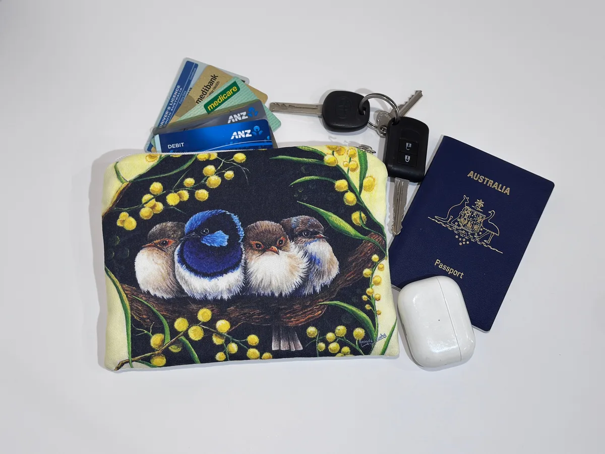 The wrens and wattle pouch beside keys, cards, a passport and earbuds, showing its size.